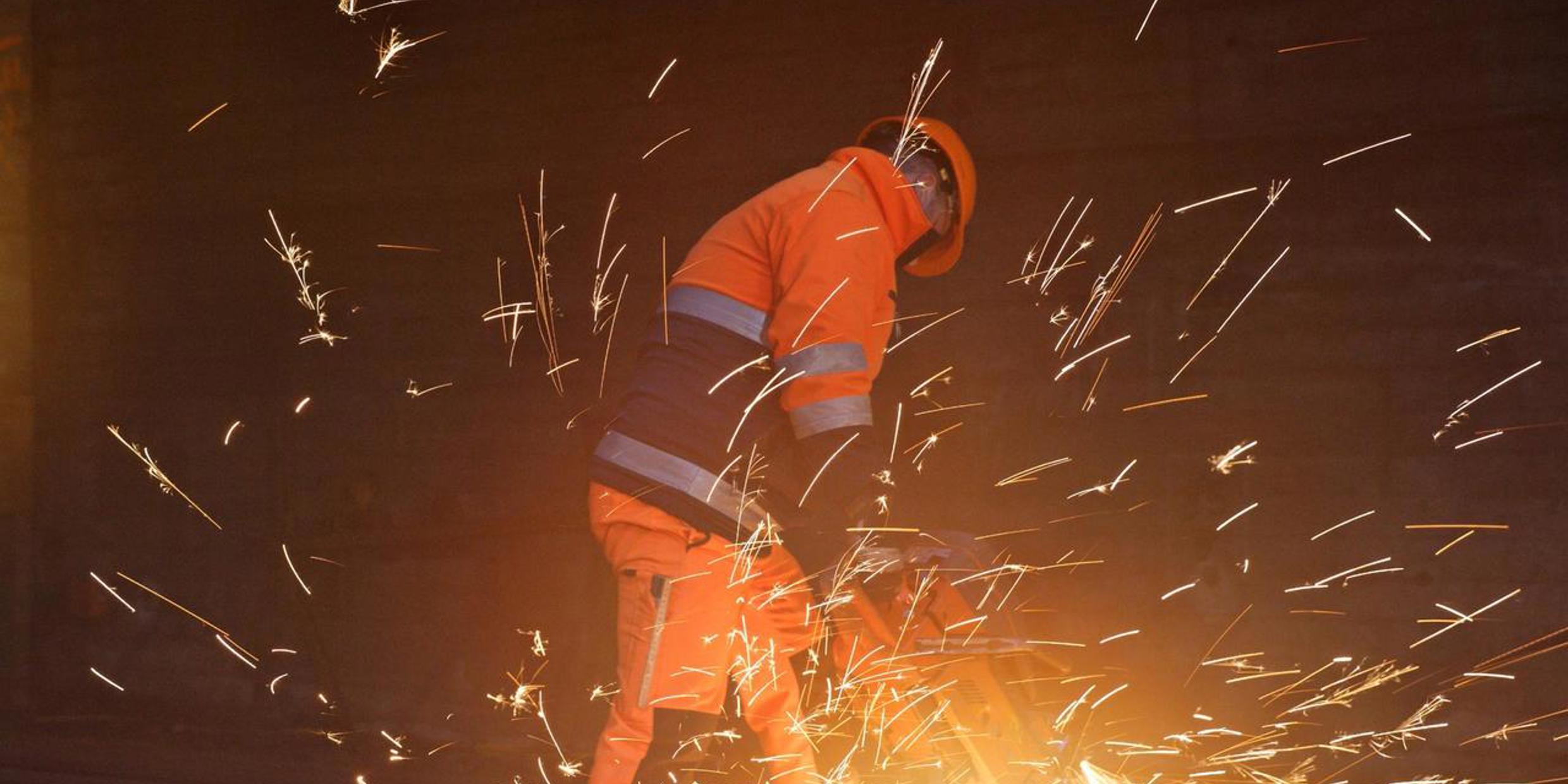 Un employé des CFF en tenue de travail orange en train de souder